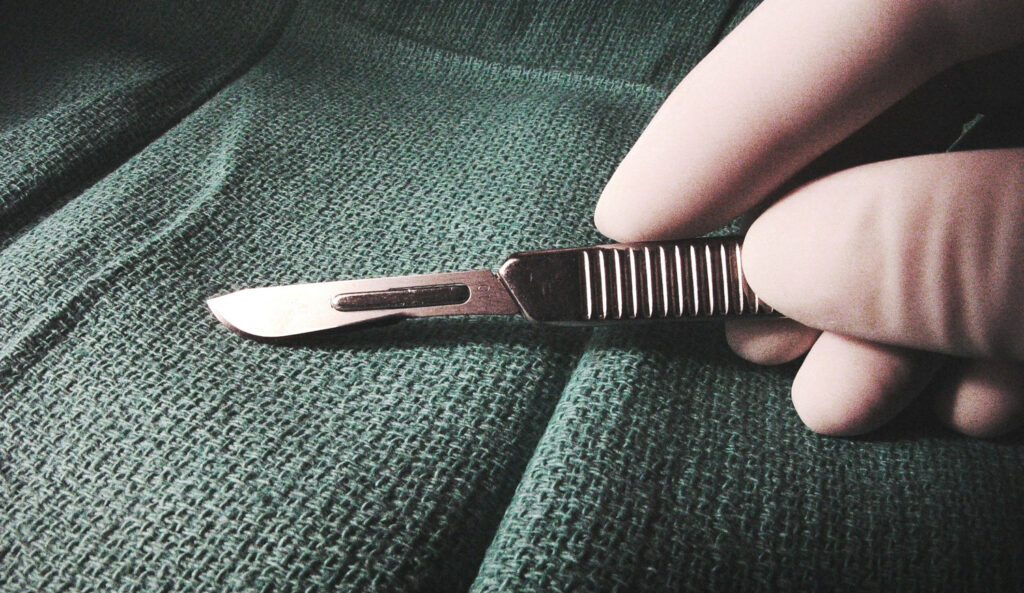 Man holds scalpel in operating theatre